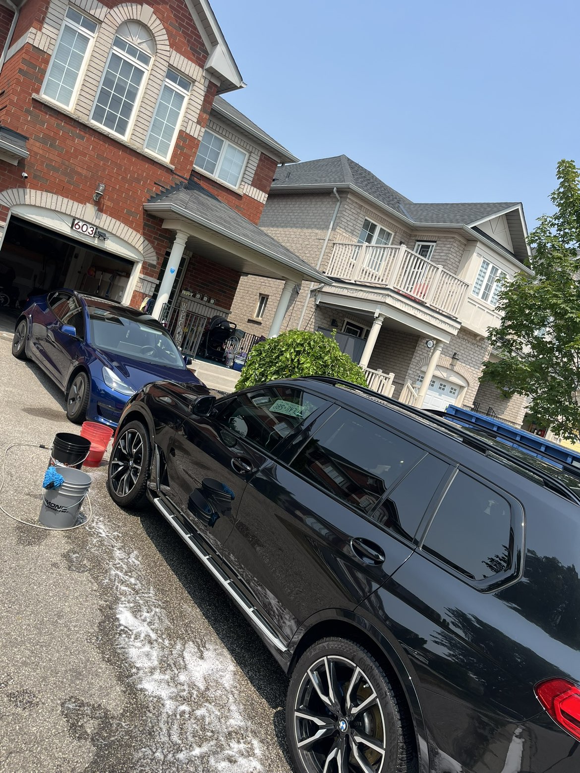 Two cars mid-wash being hand-washed with buckets and suds