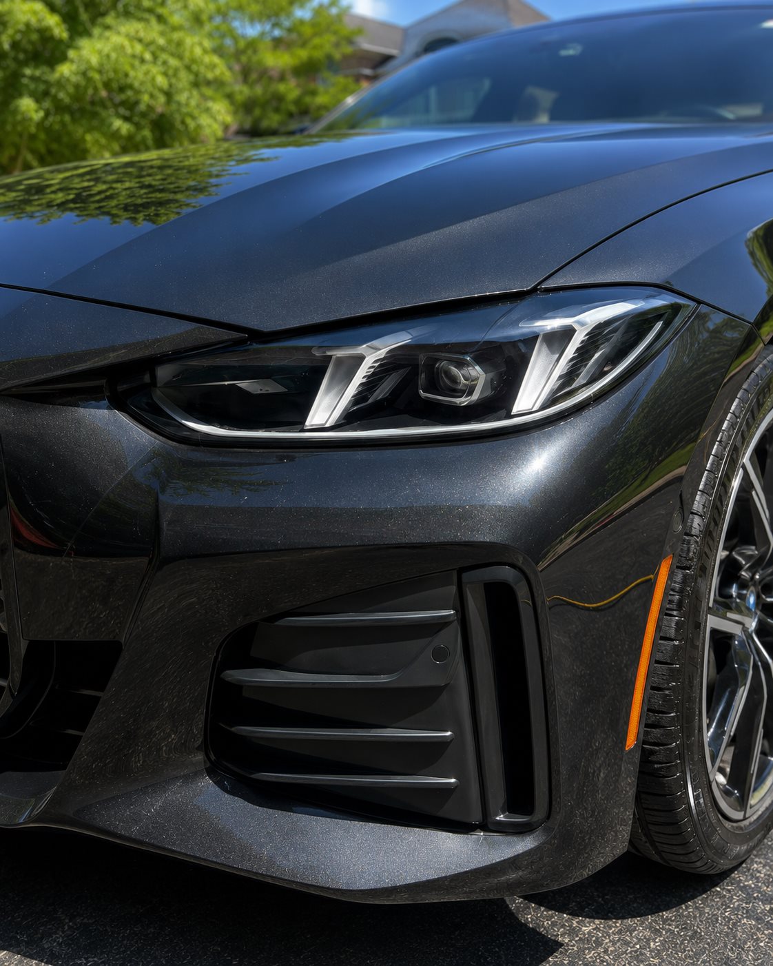 Black BMW 4 Series headlight with crisp, clear lens in the sun